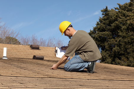 man holding a clipboard while inspecting a roof